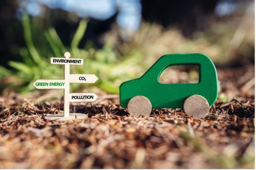 A green car next to a sign